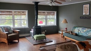 Una sala de estar acogedora con una estufa de leña, un sofá, un sillón y una lámpara.