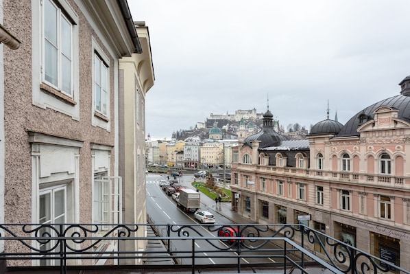 A street view with buildings, a road, and a hill with a castle in the background.