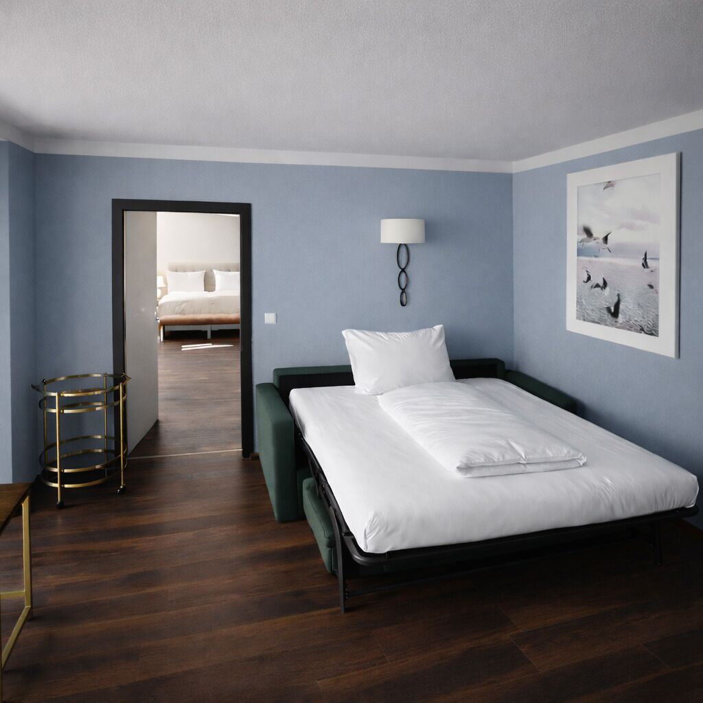 Une chambre d’hôtel avec un lit simple, une table de chevet, une lampe et un tableau encadré au mur.
