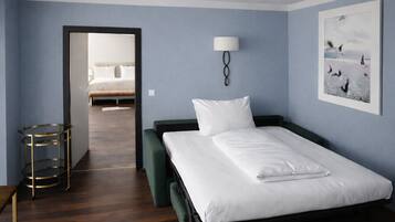 Une chambre d’hôtel avec un lit simple, une table de chevet, une lampe et un tableau encadré au mur.