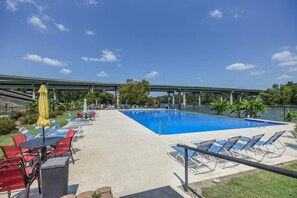 A swimming pool with lounge chairs and umbrellas, a bridge in the background, and a clear sky. - Coosa Cottage at River Rocks Landing (Gadsden)
