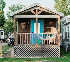 A small cabin with a wooden porch, a blue door, and a sign that reads 'Cottage.' - Coosa Cottage at River Rocks Landing (Gadsden)