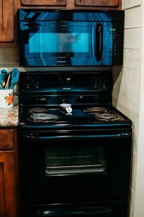 A kitchen with a black Frigidaire microwave, stove, and oven. - Coosa Cottage at River Rocks Landing (Gadsden)