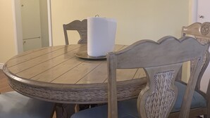Ein Essbereich mit einem runden Holztisch, Korbstühlen und einem Spiegel an der Wand.