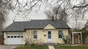 Einbungalow mit Garage, Eingangstür und einer kleinen Veranda.