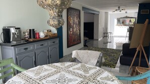 A dining area with a table covered in a patterned tablecloth, a coffee machine, and a painting on the wall. - Charming property surrounded by vineyards near St Chinian (Pierrerue)