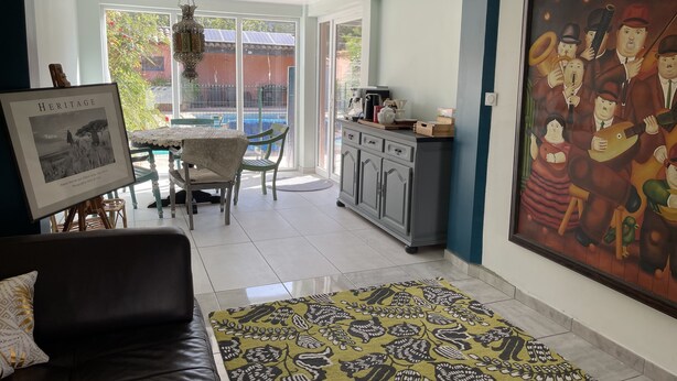 A modern living room with a sofa, a dining area with chairs and a table, a kitchen area with cabinets and a coffee machine, and a large painting on the wall. - Charming property surrounded by vineyards near St Chinian (Pierrerue)
