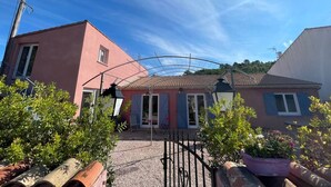 A residential area with houses, a covered patio, and a gravel driveway. - Charming property surrounded by vineyards near St Chinian (Pierrerue)