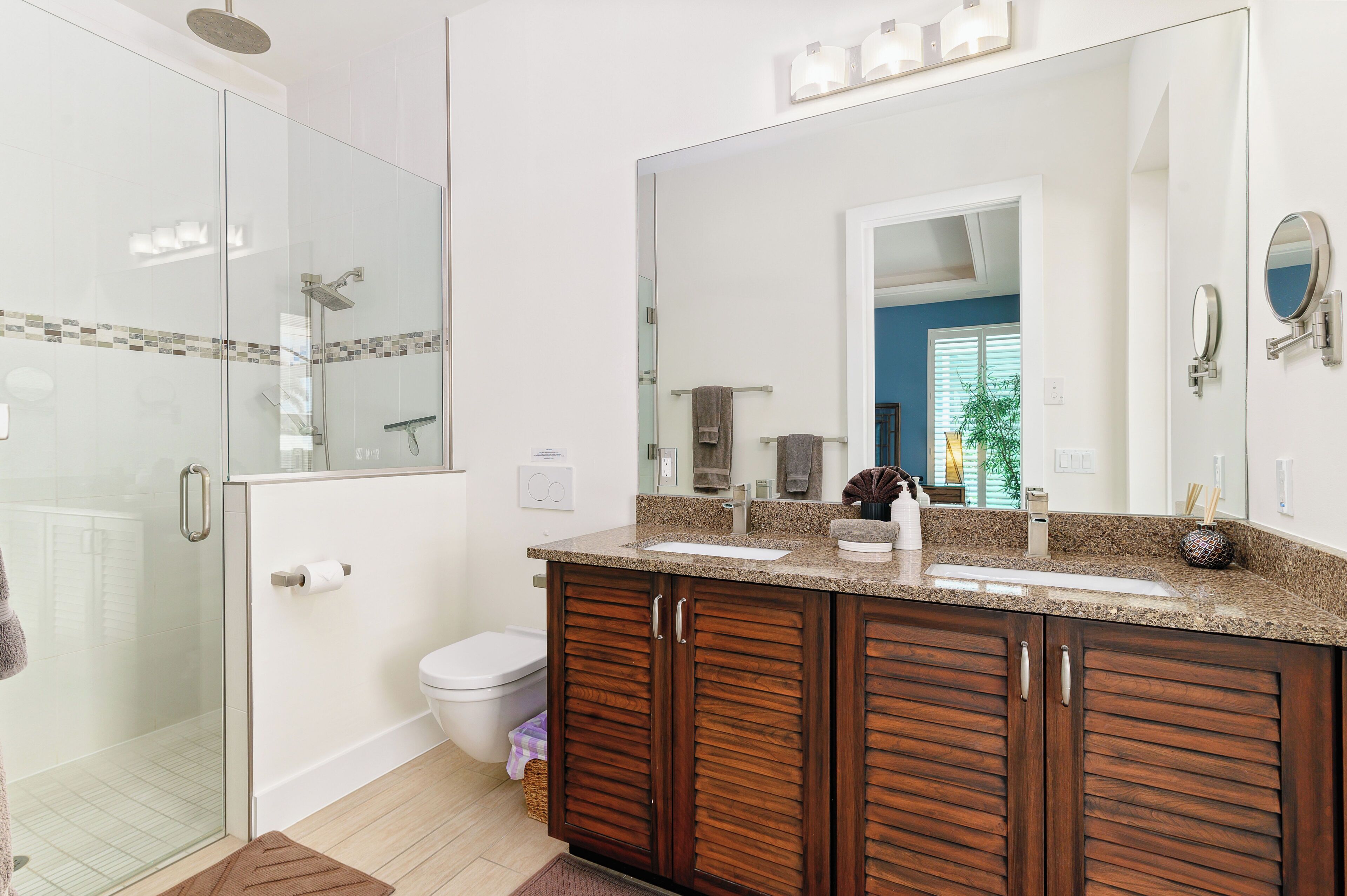 Une salle de bain moderne avec une douche à parois de verre, un meuble-lavabo double avec un grand miroir et des toilettes.