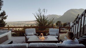 Terraza con asientos exteriores y una chimenea, con vistas a un paisaje montañoso.
