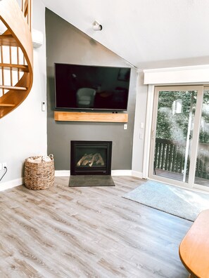 Relax in this stylish living room with a flat-screen TV, fireplace, and sliding glass door leading to an outdoor deck.