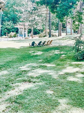 Relax in style with Adirondack chairs amidst lush greenery and a serene gazebo.