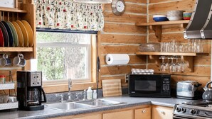 Cozinha com armários de madeira, cafeteira, micro-ondas, torradeira e fogão.
