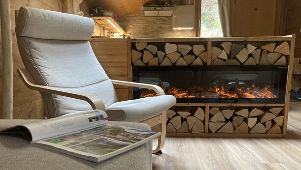 A cozy room with a fireplace, a comfortable chair, and a magazine on the floor. - Luxury chalet with panoramic views in the Lötschental, with private carport  (Kippel)