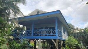Um edifício azul com varanda, rodeado por vegetação exuberante.