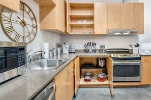 Una cucina moderna con mobili in legno, elettrodomestici in acciaio inossidabile e un grande orologio a parete.