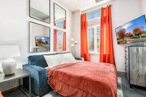 Una camera da letto moderna con un letto, una TV e una scrivania.