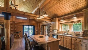 A log cabin interior with a central island kitchen, dining area, and a telescope in the corner. - Montana Wildflower Lodge~sleeps 10 (Red Lodge)