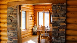 A log cabin interior with a stone fireplace, wooden dining table, and chairs. - Montana Wildflower Lodge~sleeps 10 (Red Lodge)
