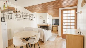 A modern kitchen with a dining area, wooden ceiling, and a large window. - Cosy apartment, terrace, parking and ski room (Mas de Ribafeta)