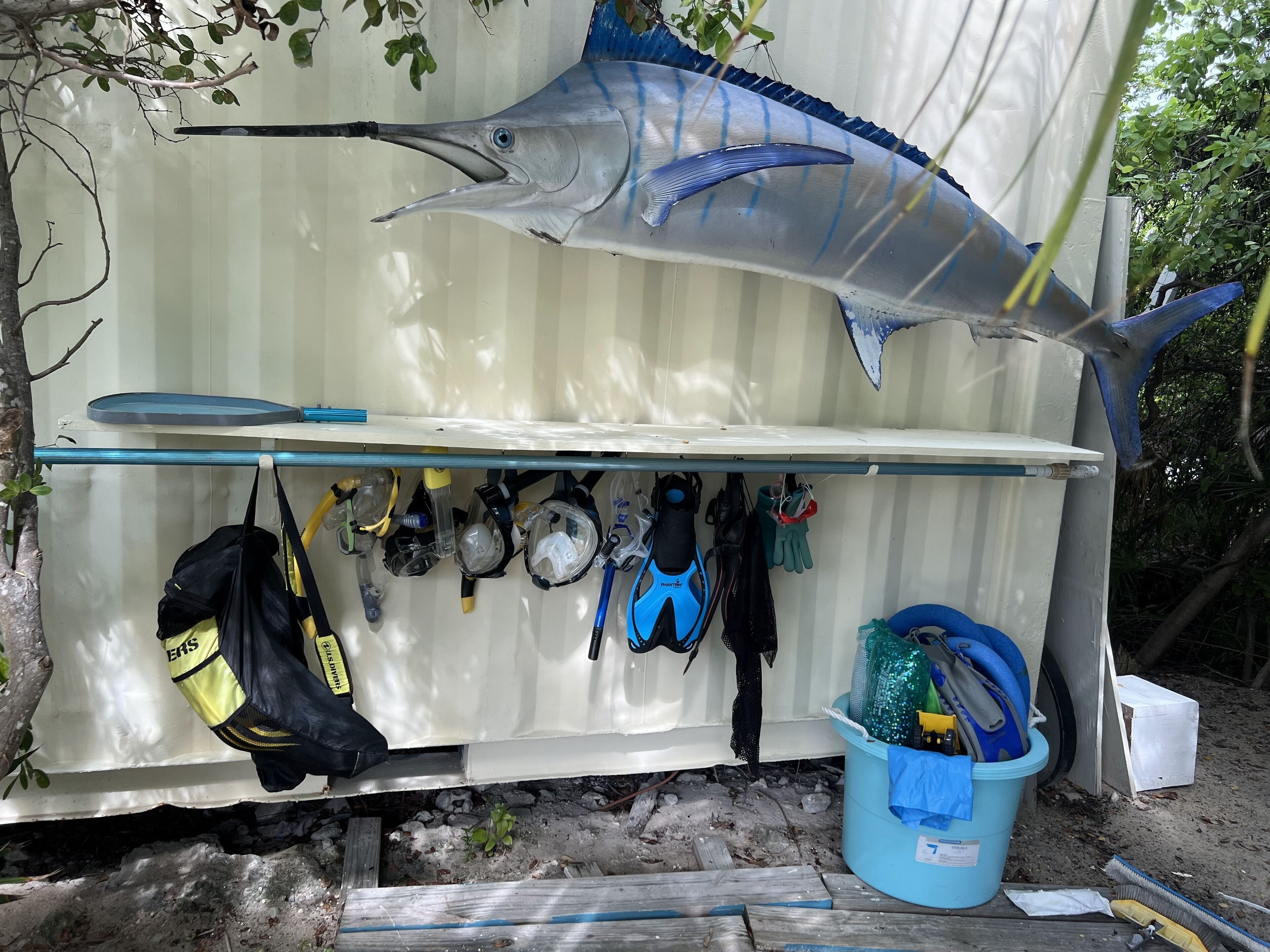 Un espacio de almacenamiento con un modelo grande de pez, equipo de buceo y un cubo.