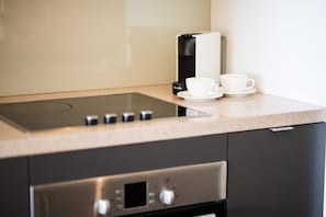 A modern kitchen with a built-in induction cooktop, a coffee maker, and a white cup on the counter. - Rendez-vous Chez Leah (Airlie Beach)