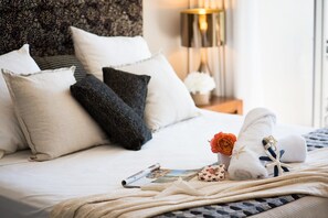 A neatly made bed with pillows, a rolled towel, and a small flower arrangement. - Rendez-vous Chez Leah (Airlie Beach)