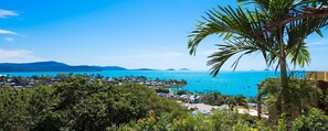 A coastal view with a clear sky, a body of water, and a dense green area in the foreground. - Rendez-vous Chez Leah (Airlie Beach)