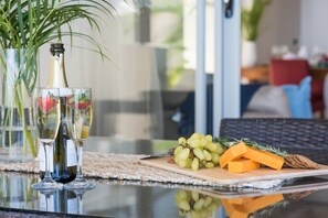 A table with two glasses of wine, a bottle, and a wooden board with grapes, cheese, and crackers.