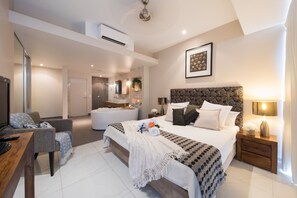 Habitació d'hotel moderna amb un llit gran, escriptori, cadira, bany i zona d'estar.