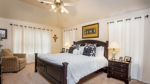 A bedroom with a bed, a nightstand, a chair, and a ceiling fan. - Super COZY 4 bdr home w beautiful gazebo terrace!! (Magnolia)