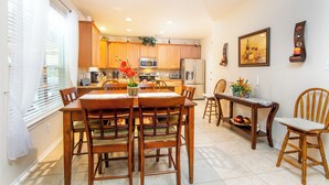 A spacious kitchen with wooden cabinets, a dining table with chairs, and a small dining area with a side table. - Super COZY 4 bdr home w beautiful gazebo terrace!! (Magnolia)