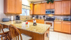 A kitchen with wooden cabinets, granite countertops, a microwave, stove, and a sink. - Super COZY 4 bdr home w beautiful gazebo terrace!! (Magnolia)