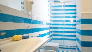 A bathroom with a white sink, a yellow loofah, and a shower with blue and white striped tiles. - RED LION APARTMENT x6 (Sorrento)
