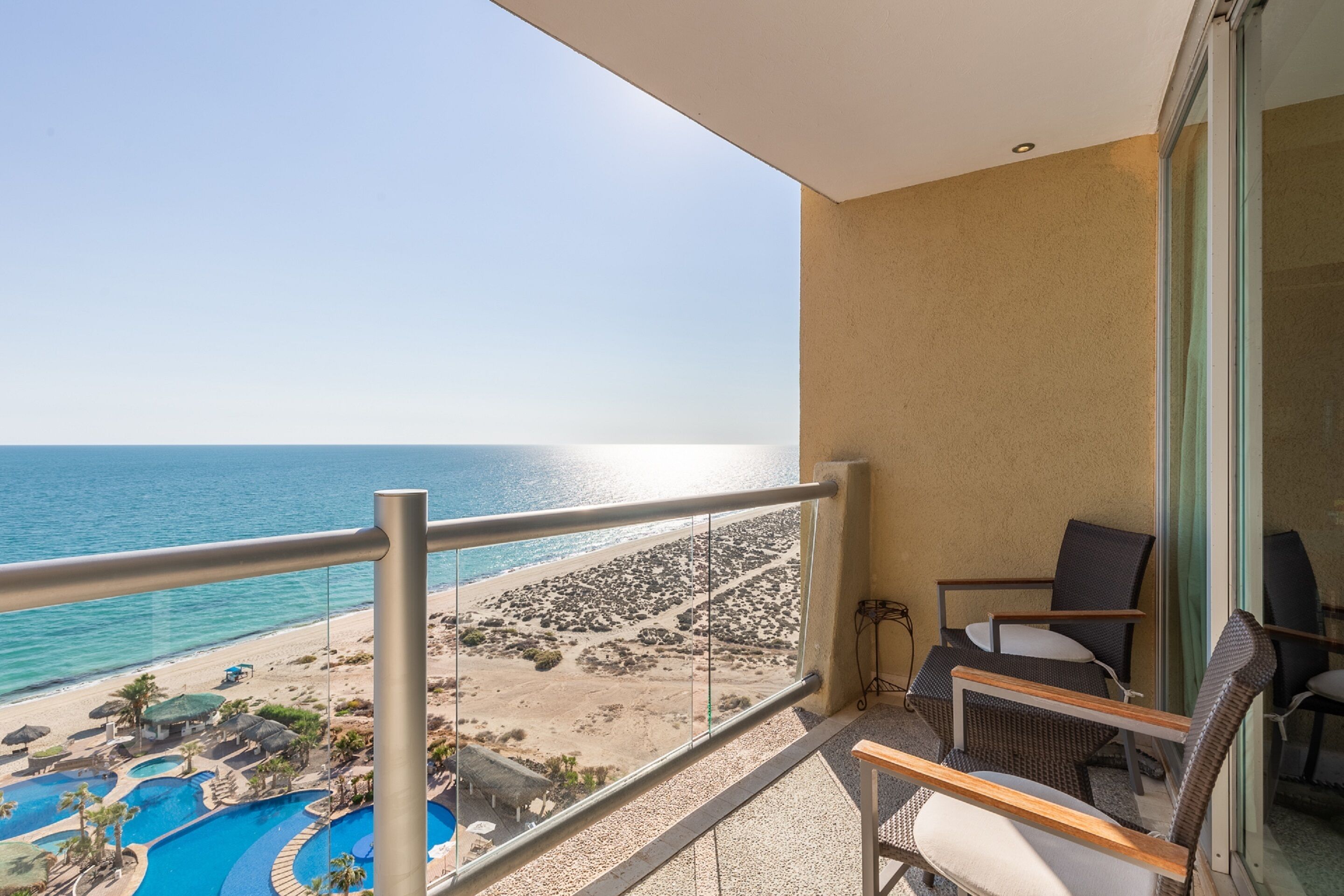 Un balcon avec vue sur une plage et une piscine.