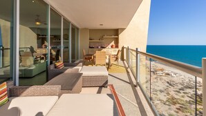A balcony with a view of the ocean, furnished with sofas and a dining table. - Encanto Living 1104 by Kivoya (Puerto Peñasco)