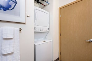 Una lavanderia con lavatrice e asciugatrice, una porta di legno e un quadro appeso al muro.