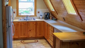 A kitchen with wooden cabinets, a countertop, a window, and a built-in oven. - Riverside A-Frame Close to RMNP, 2 BDR King, 1 BTH, Fireplace, Adventure Awaits (Lyons)