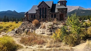 A stone church with a bell tower, set against a mountainous backdrop. - Riverside A-Frame Close to RMNP, 2 BDR King, 1 BTH, Fireplace, Adventure Awaits (Lyons)