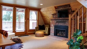 A cozy living room with a fireplace, wooden walls, and a comfortable seating area. - Riverside A-Frame Close to RMNP, 2 BDR King, 1 BTH, Fireplace, Adventure Awaits (Lyons)