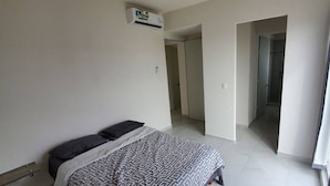 A bedroom with a bed, a wardrobe, and an air conditioning unit.