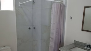 A bathroom with a shower, toilet, and sink.
