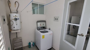 A compact laundry room with a front-loading washing machine, a stacked washer and dryer, and a water heater.