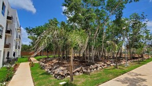 A landscaped area with trees, a pathway, and a building with balconies.