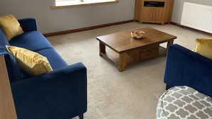A living room with a blue sofa, a wooden coffee table, and a television on a wooden stand.