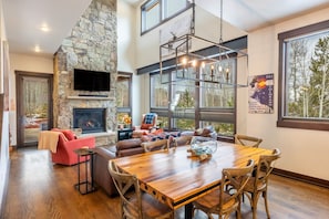 A spacious living area with a stone fireplace, a large wooden dining table, and a comfortable seating arrangement.