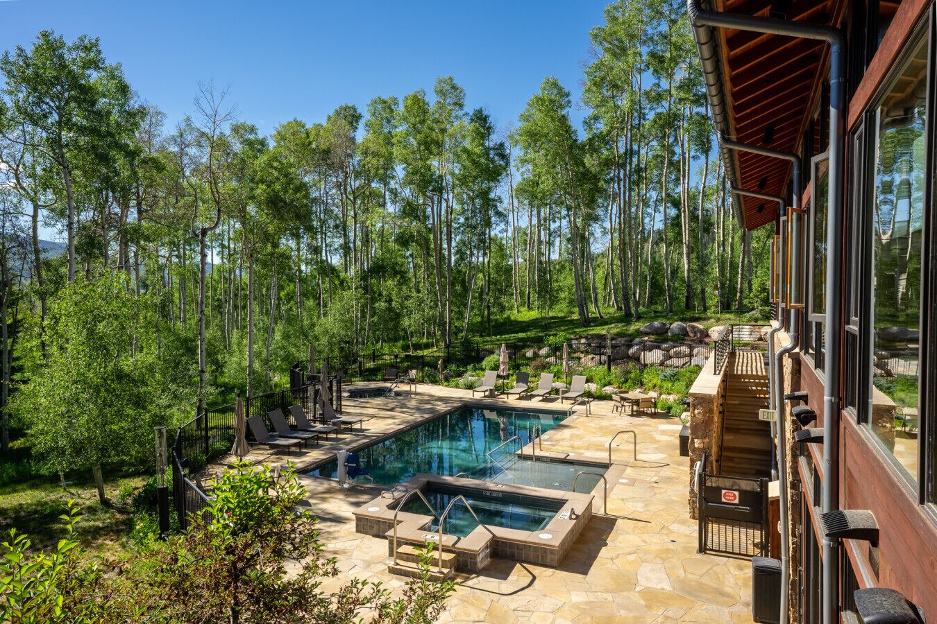 Un espace piscine comprenant un jacuzzi, des chaises longues et une terrasse en pierre.