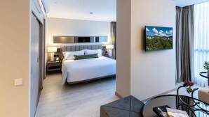 Moderni hotellihuone, jossa on suuri sänky, työpöytä tuolilla, taulu seinällä ja näkymä ulos ikkunasta.
