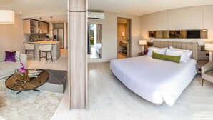 Moderni hotellihuone, jossa on suuri sänky, sohva, sohvapöytä ja pieni keittiö.