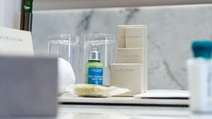 Kylpyhuoneen tasolla on hygieniatarvikkeita, kuten pullo vartalovoide, hammasharja ja kannettava tietokone.